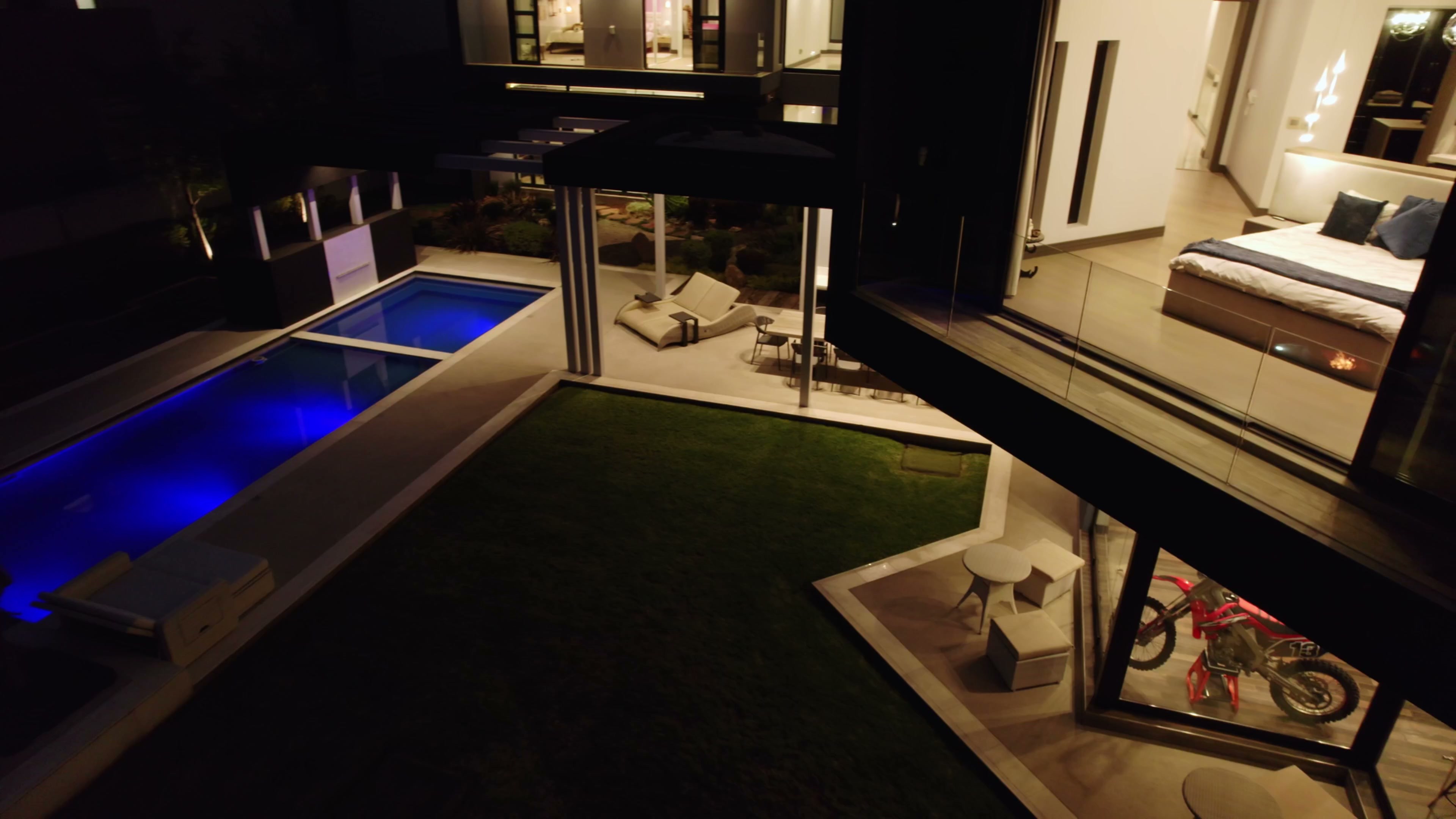 Aerial evening view of the 763 Eco Estate residence with pool and illuminated interiors